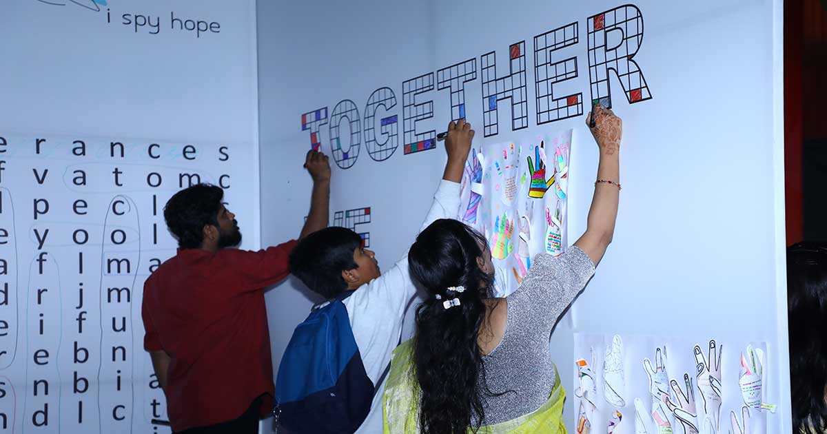 Participants create art on a wall at Afflatus 2023, showcasing teamwork and creativity.