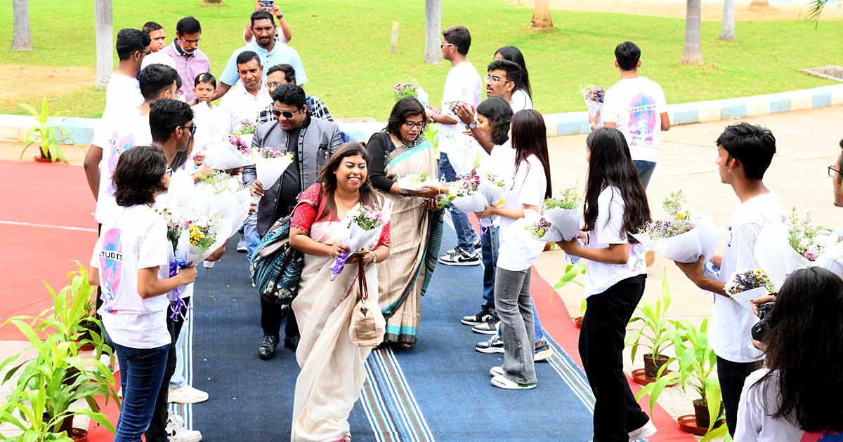 Students in white T-shirts greet guests with bouquets at the Teacher’s Day celebrations 2023 at JIRS.