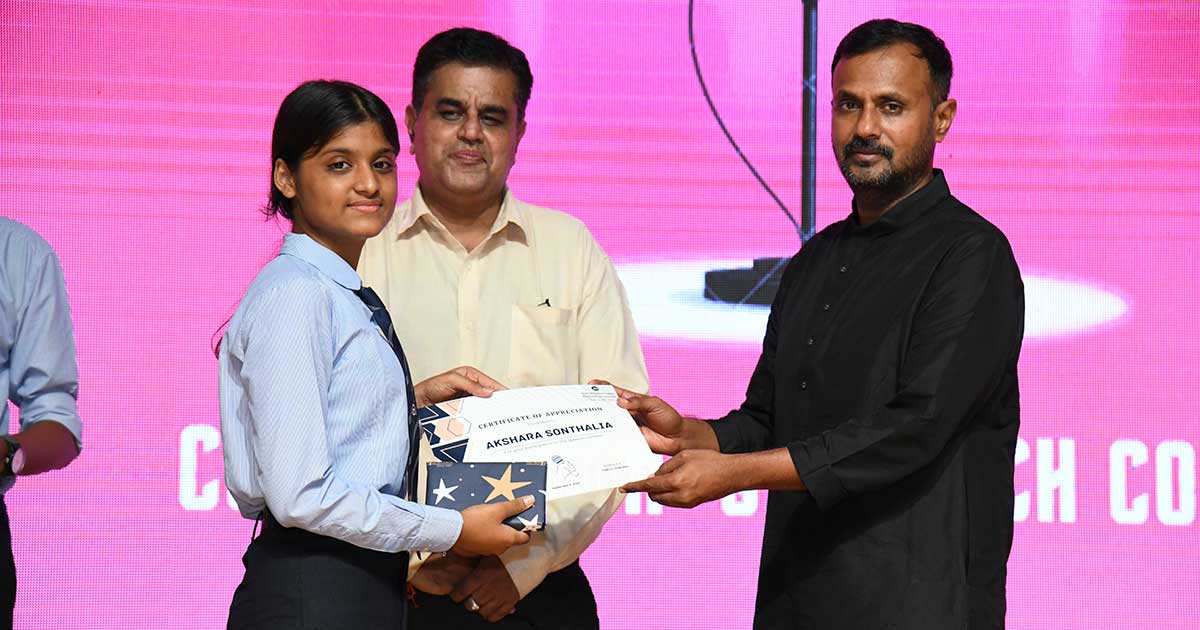 Young girl Akshara Sonthalia receives a certificate during the Toastmasters Program at JIRS.